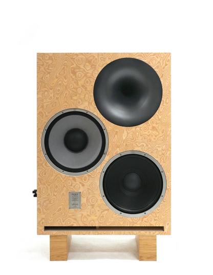 A custom wooden speaker cabinet with a light natural plywood faceplate, featuring a large black dome driver at the top and two larger black and gray woofers below, supported by two small wooden feet on a white background.