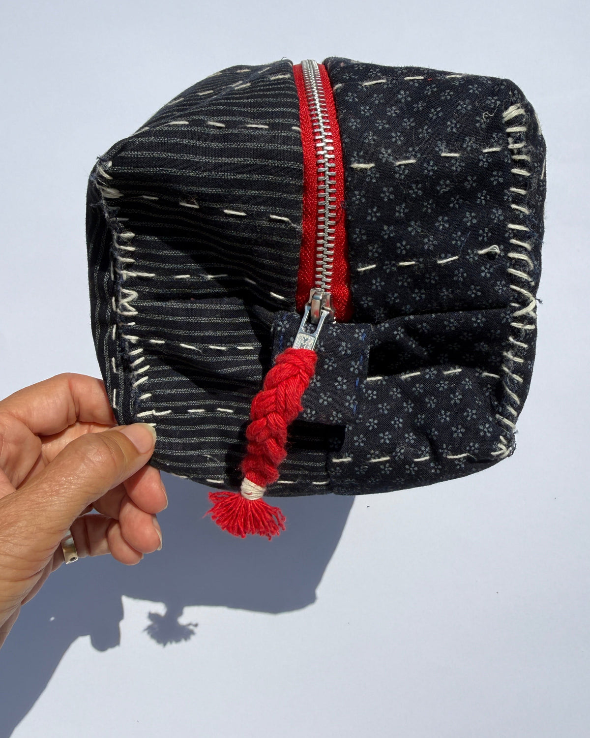 A handmade fabric metal zippered pouch with a dark navy and white Japanese fabric and quilted design.