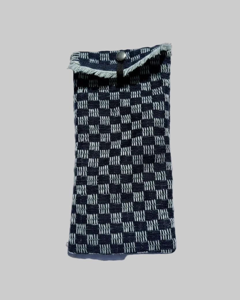 A small woven fabric pouch or sleeve with a blue  and off-white checkerboard pattern and frayed trim.
