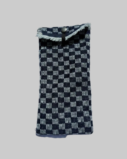 A small woven fabric pouch or sleeve with a blue  and off-white checkerboard pattern and frayed trim.