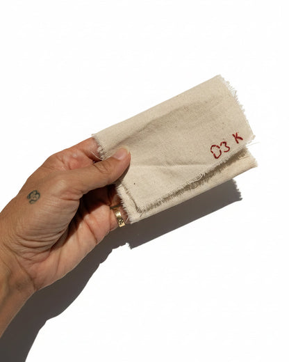 light beige fabric with frayed edges and red printed text reading 'D3 K' against a plain light background. Vitamin bags, pouch, wallet,  purse. 